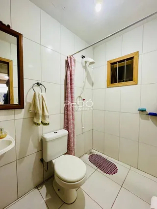 Foto de um banheiro com piso e paredes brancas em cerâmica.