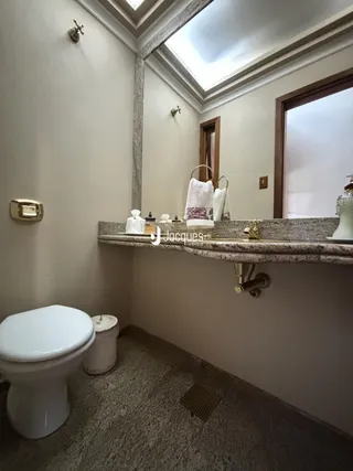 Foto de um banheiro com bancada de mármore e vaso sanitário branco.