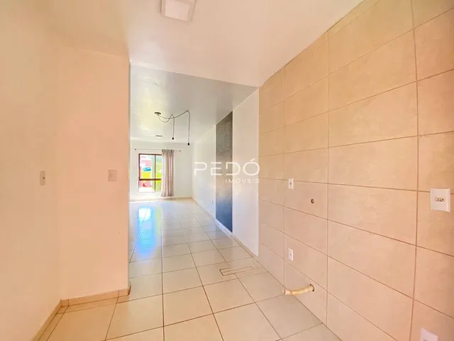 Corredor interno de uma residência com piso de cerâmica claro.