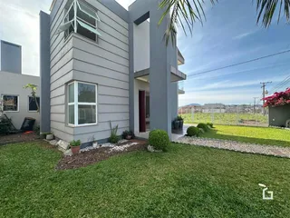 Fachada de uma casa moderna em Lajeado, Brasil, com jardim gramado e cerca no fundo.