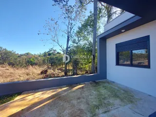 Vista externa de um pátio com vegetação ao fundo.
