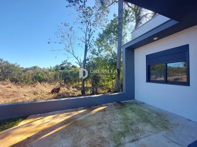 Vista externa de um pátio com vegetação ao fundo.