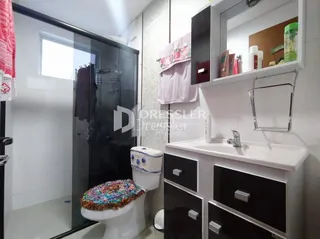Foto de um banheiro interno com box de vidro e louças brancas.
