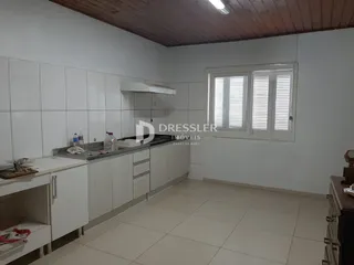 Vista interna de uma cozinha com armários brancos e piso claro.