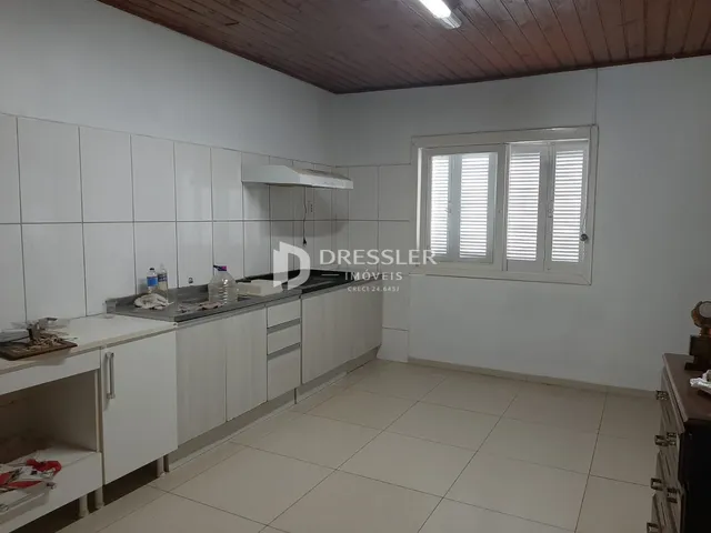 Vista interna de uma cozinha com armários brancos e piso claro.