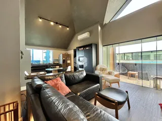 Sala de estar com pé direito alto e grande abertura para a área externa.