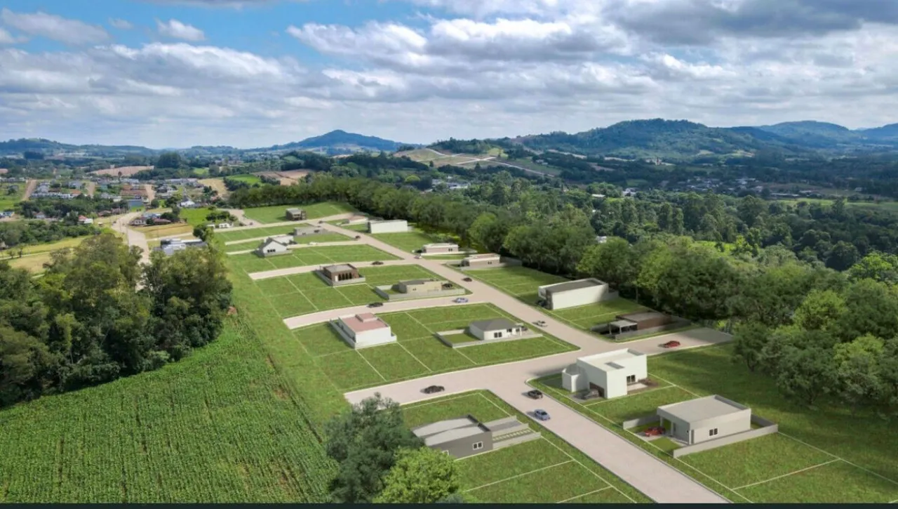 Vista aérea de um loteamento residencial com terrenos verdes e estruturas.