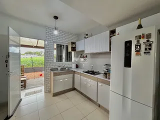 Vista da cozinha moderna com armários brancos e piso claro.