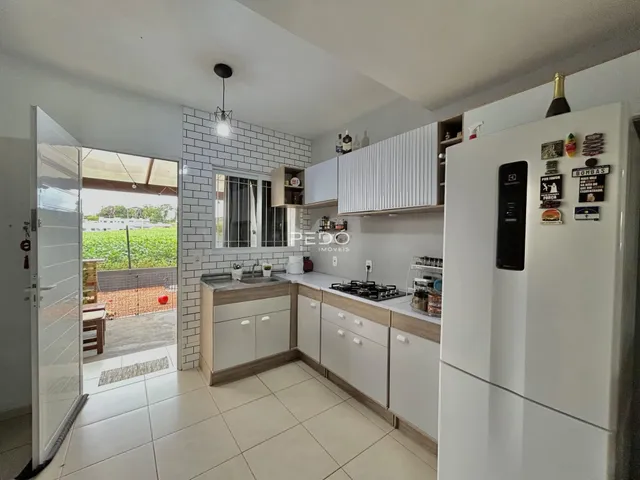 Vista da cozinha moderna com armários brancos e piso claro.