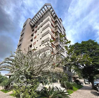 Fachada de um prédio residencial em Lajeado, Brasil, com vegetação na frente.