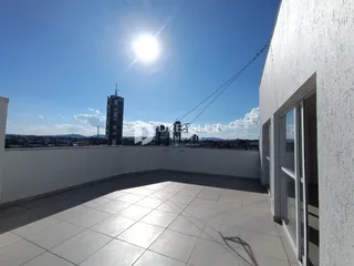 Vista de um terraço com piso de cerâmica e paisagem urbana.