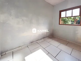 Uma foto interna mostra uma sala com paredes claras e piso de cerâmica.