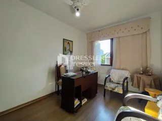 Sala de estar com piso de madeira e cortinas claras.