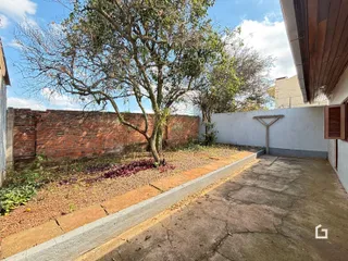 Vista externa de uma propriedade com muro de tijolos e vegetação.