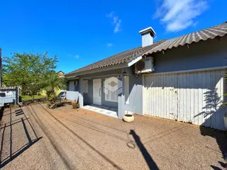 Fachada de uma residência em Lajeado, Brasil, com portão de madeira e entrada de cascalho.