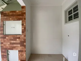 Interior de um ambiente com parede de tijolos aparentes e revestimento branco.