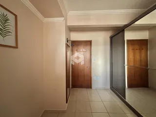 Hall de entrada com portas de madeira e piso cerâmico claro.