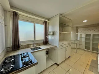Vista da cozinha de um imóvel em Lajeado, Brasil, com bancadas e armários brancos.