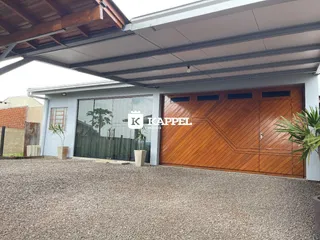 A foto mostra a fachada de uma residência com garagem de madeira e piso de cascalho.