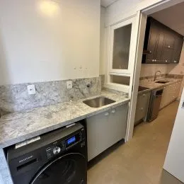 Foto de uma bancada de cozinha com eletrodomésticos em um imóvel.