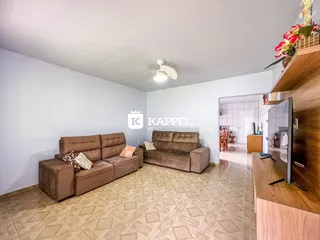 Uma sala de estar com sofá de couro marrom e piso de cerâmica clara.