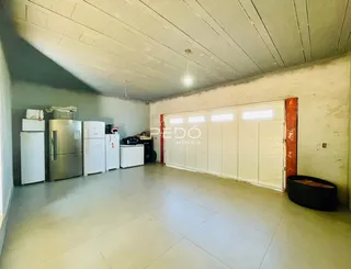Foto do interior de um espaço amplo com piso de cerâmica e porta de garagem.