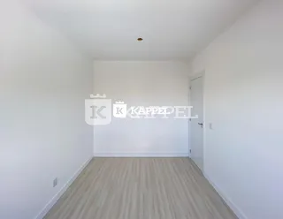 Foto de um cômodo interno com piso de madeira clara e paredes brancas.