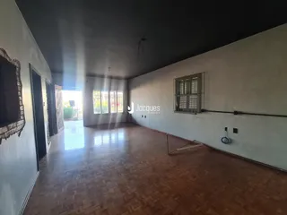 Interior de uma sala com piso de madeira e paredes brancas.