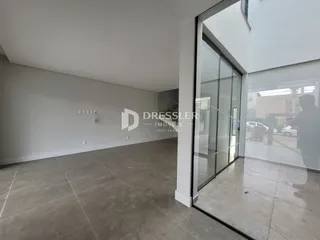 Interior de uma sala ampla com piso de cerâmica e paredes brancas.