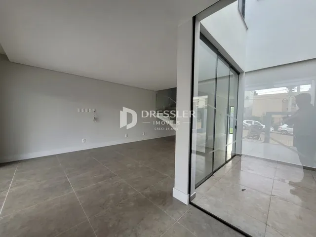 Interior de uma sala ampla com piso de cerâmica e paredes brancas.