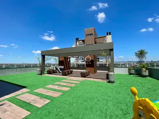 Vista externa de um jardim com área de lazer e estrutura de pérgola em uma residência.