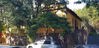 Fachada de uma residência amarela em Lajeado, Brasil, com vegetação densa ao redor.