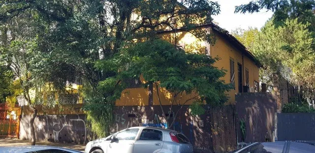 Fachada de uma residência amarela em Lajeado, Brasil, com vegetação densa ao redor.