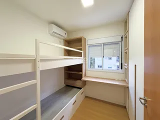 Quarto com estrutura de beliche e estantes de madeira em um imóvel.