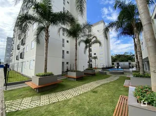 Vista da fachada de um prédio residencial em Lajeado, Brasil, com jardim e palmeiras.