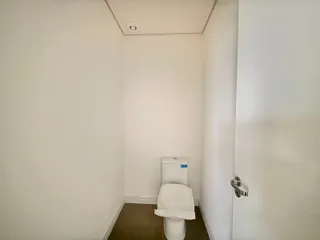 Foto de um corredor com paredes brancas e um vaso sanitário.