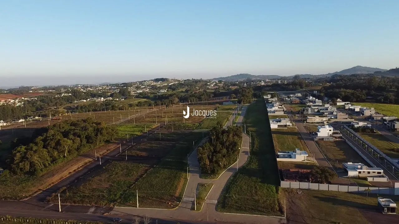 Vista aérea de uma área de terreno com vegetação e estruturas dispersas.