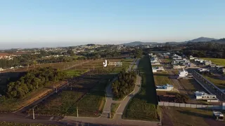 Vista aérea de uma área de terreno com vegetação e estruturas dispersas.