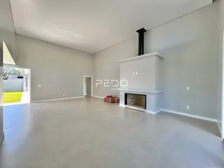 Ambiente interno de uma sala ampla com paredes cinzas e piso claro.