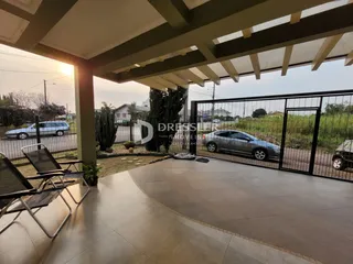 Vista da fachada de uma propriedade em Lajeado, Brasil, com portão de ferro e área pavimentada.