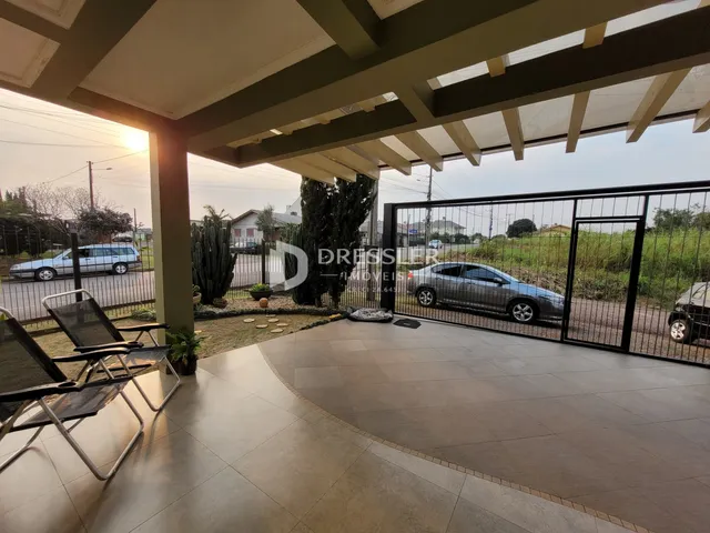 Vista da fachada de uma propriedade em Lajeado, Brasil, com portão de ferro e área pavimentada.