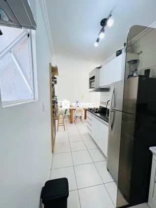 Foto interna de uma cozinha com armários brancos e piso de cerâmica.
