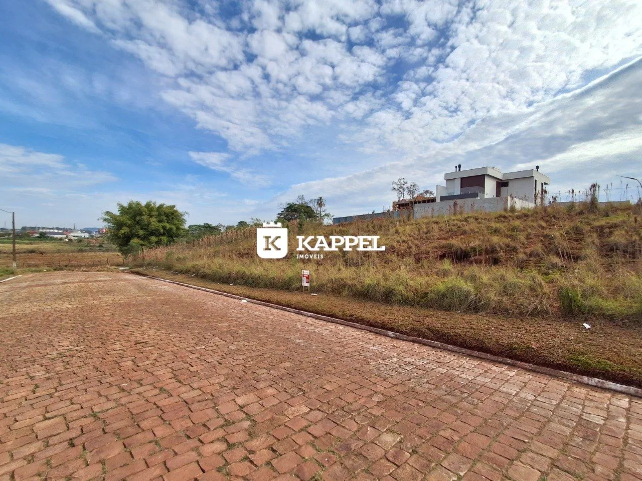 Vista externa de uma propriedade em Lajeado, com uma área pavimentada em primeiro plano e vegetação seca ao fundo.