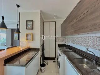 Vista da cozinha moderna com armários de madeira e bancadas de granito.