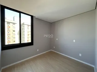 Ambiente interno com piso de madeira clara e grande janela.
