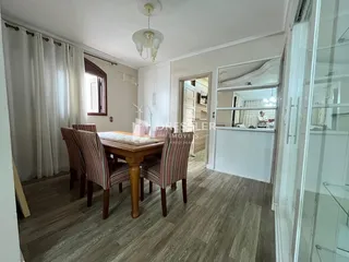 Uma sala de jantar com mesa de madeira e cadeiras no interior da residência.