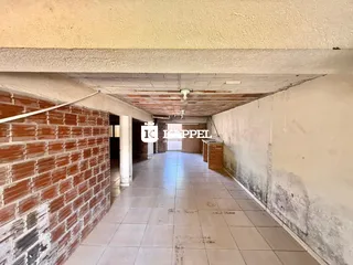 Corredor interno com paredes de tijolo aparente e piso de cerâmica.