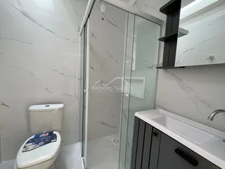Banheiro com revestimento em mármore e box de vidro.