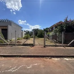 Vista externa da propriedade mostrando uma cerca e vegetação no dia.