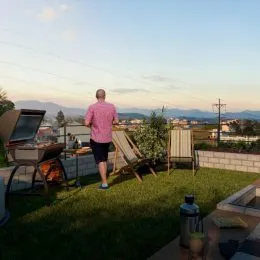 Vista externa de um jardim com vegetação e paisagem ao fundo.